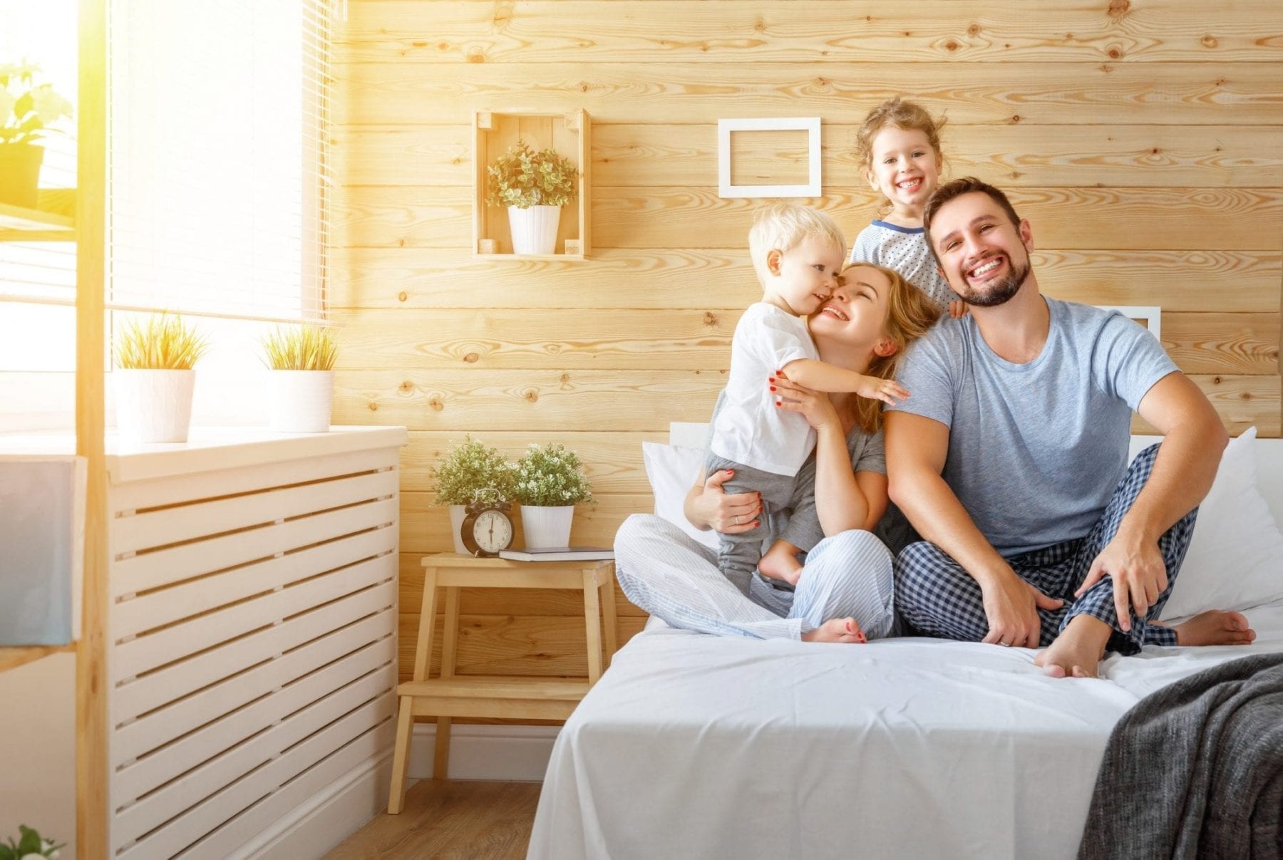 Happy family mother father and children daughter and son in bed bedroom