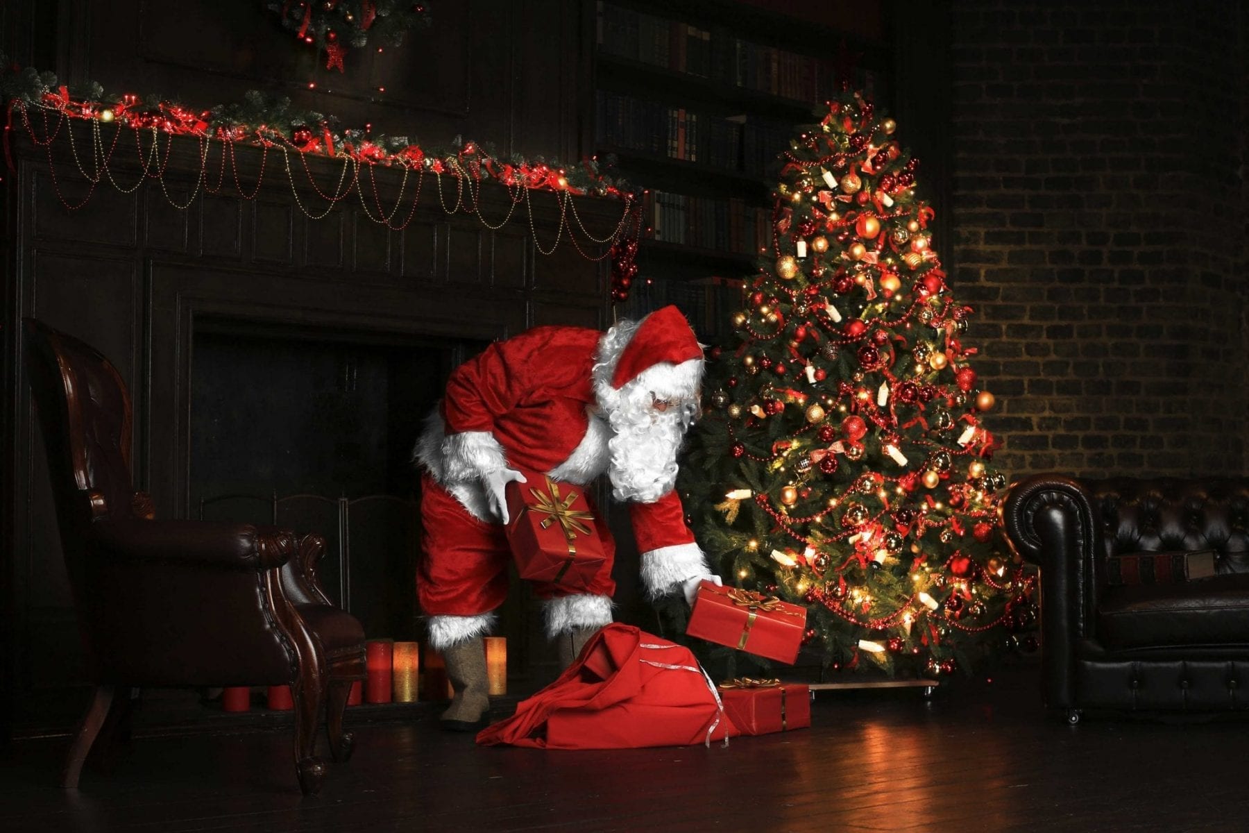 Santa placing presents under a Christmas tree