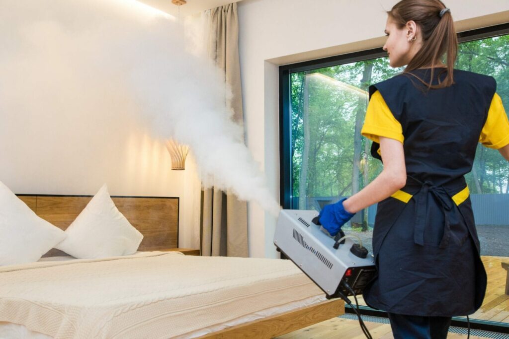 Woman spraying steam from machine in bedroom