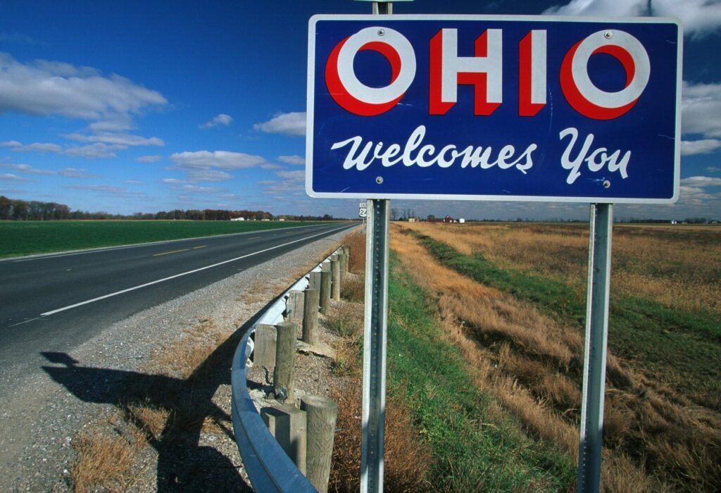 Welcome to Ohio Sign with pastoral background blue sign white lettering with red outline