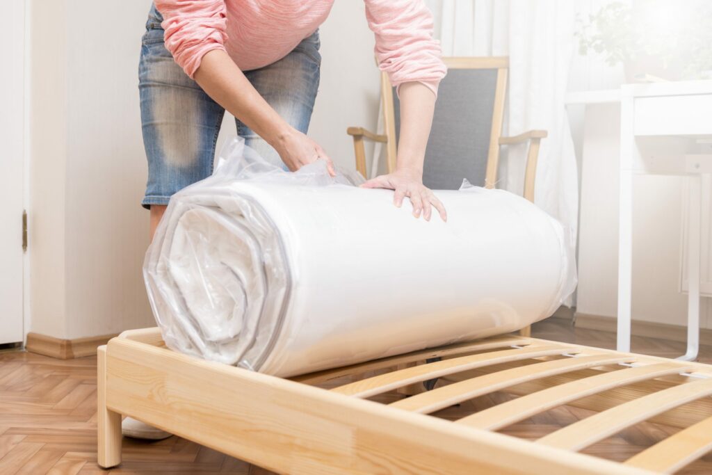 Woman unrolling new mattress still in plastic