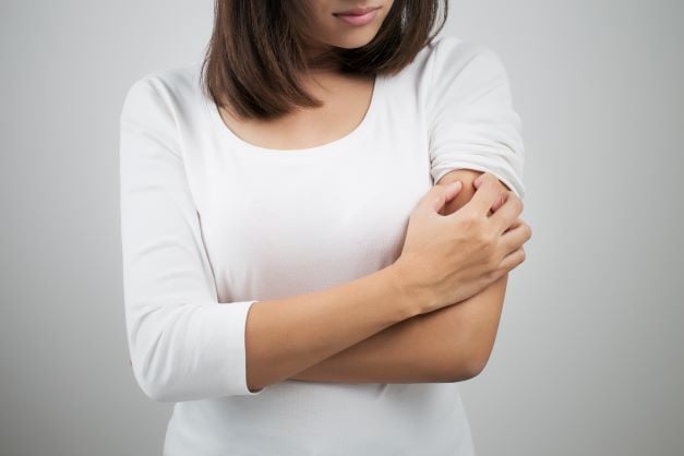 A woman scratching her arms