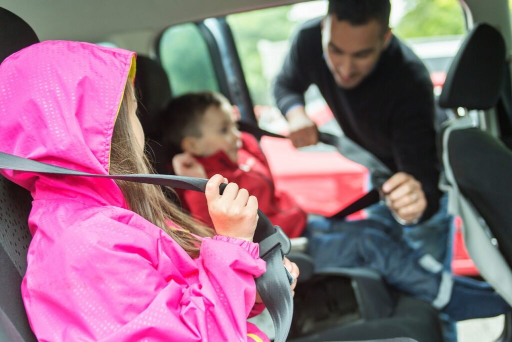 Father buckling children into car seats