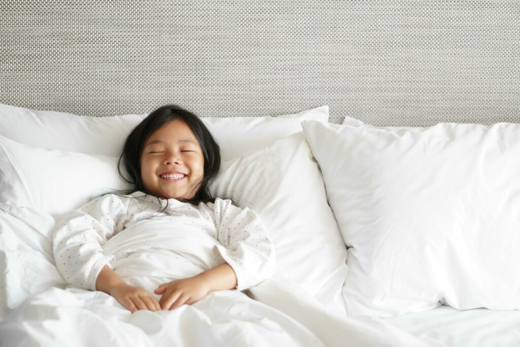 Young girl smiling in white bed