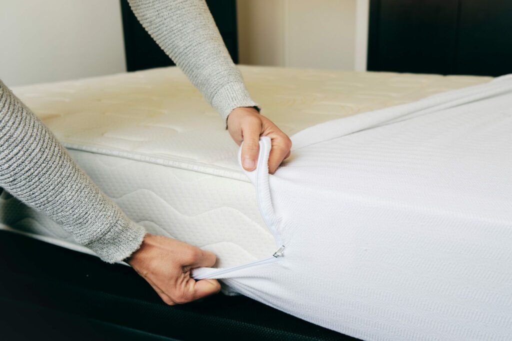 Closeup of a man covering a mattress with a white mattress protector