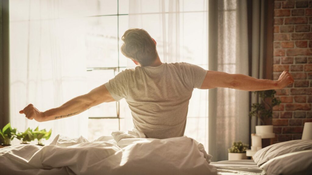Man stretching while sitting on side of bed